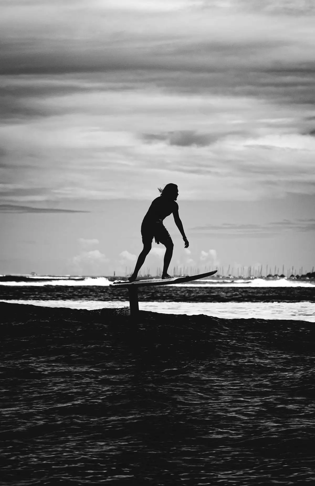 Schwarz-Weiß-Silhouette eines Foilers über dem Wasser, das Board schwebt über der Oberfläche